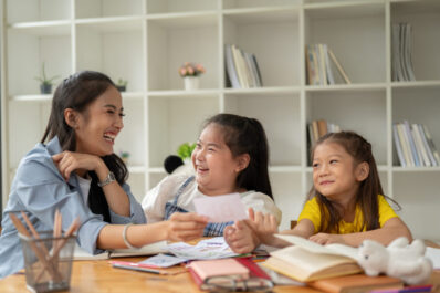 Two Asian girls are laughing and enjoying studying English alphabet flashcards with a teacher Two adorable young Asian girls are laughing and enjoying studying English alphabet flashcards with a private teacher at home. preschool, kindergarten, elementary school
